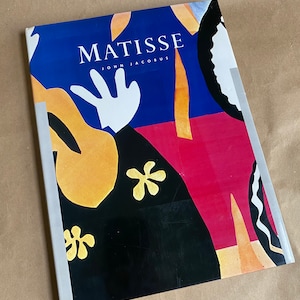 May include: A book titled "Matisse" by John Jacobus. The cover features a colorful abstract design with yellow, red, blue, black, and white shapes.