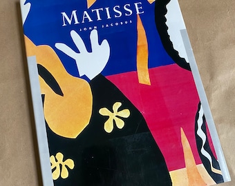 Puede incluir: Un libro titulado "Matisse" de John Jacobus. La portada presenta un diseño abstracto colorido con formas amarillas, rojas, azules, negras y blancas.