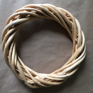 May include: A natural woven wreath made of light brown twigs, perfect for decorating a door or wall.
