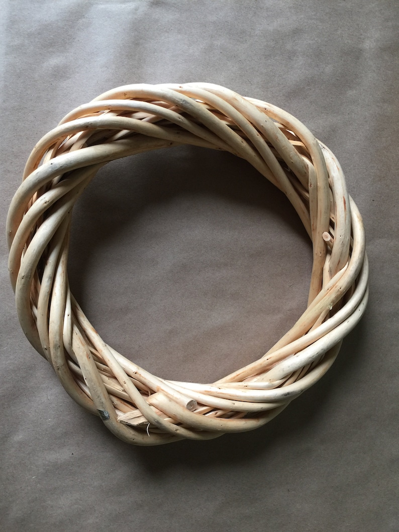 May include: A natural woven wreath made of light brown twigs, perfect for decorating a door or wall.