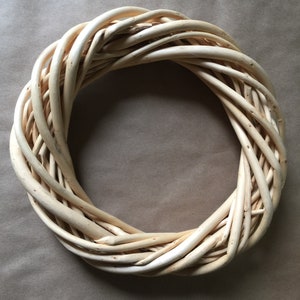 May include: A natural woven wreath made of light brown twigs, perfect for decorating a door or wall.