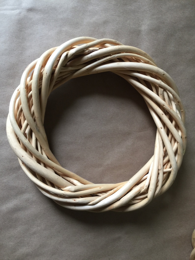 May include: A natural woven wreath made of light brown twigs, perfect for decorating a door or wall.