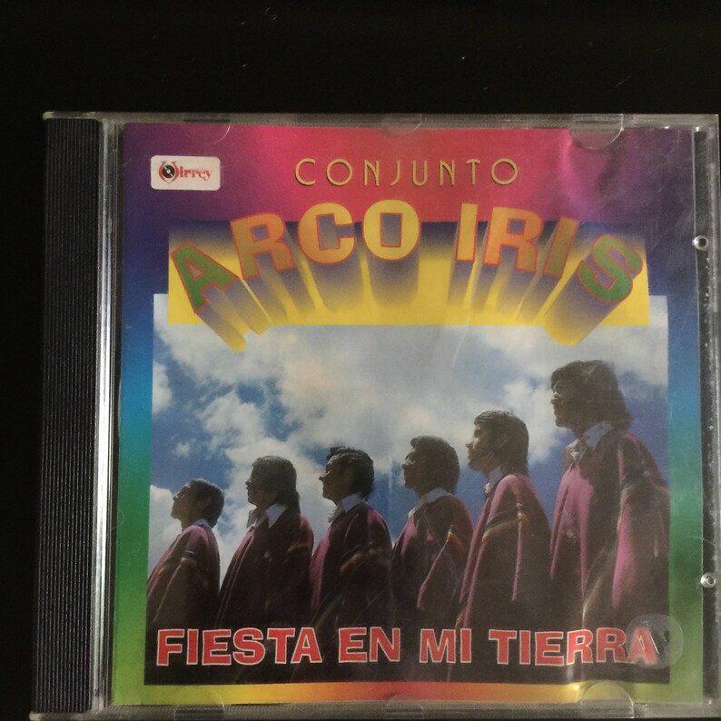Puede incluir: Una caja de CD con una imagen colorida de un grupo de hombres con ropa tradicional. El texto "CONJUNTO ARCO IRIS FIESTA EN MI TIERRA" est&aacute; impreso en la parte delantera de la caja.