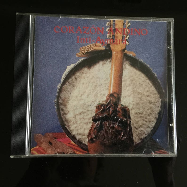 May include: A CD case with a colorful image of a wooden musical instrument with the text "CORAZ&Oacute;N ANDINO Inti-Aymar&aacute;" on the front.