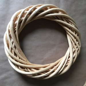 May include: A natural woven wreath made of light brown twigs, perfect for decorating a door or wall.