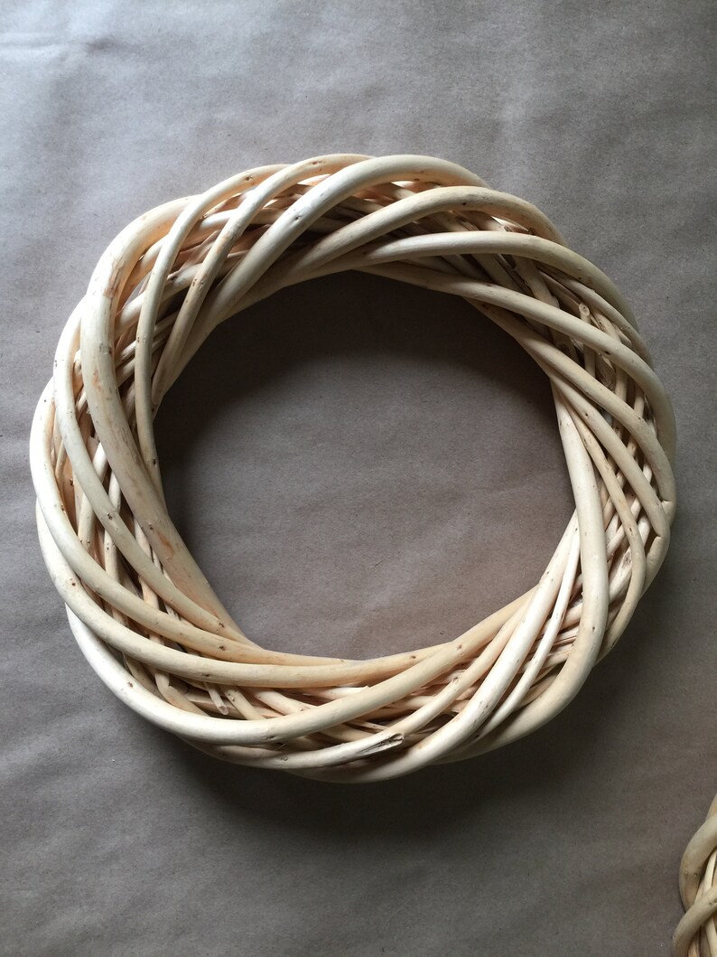May include: A natural woven wreath made of light brown twigs, perfect for decorating a door or wall.