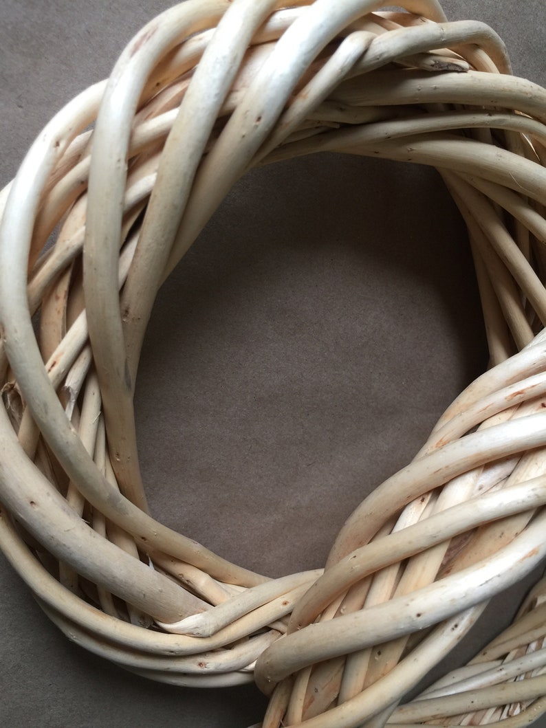 May include: A natural woven wreath made of light brown twigs, perfect for decorating a door or wall.
