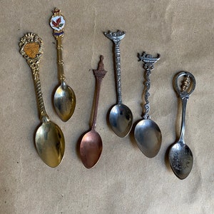 Puede incluir: Seis cucharas en miniatura con diferentes diseños y acabados. Las cucharas están hechas de plata, oro y cobre. Cada cuchara tiene un diseño único, incluyendo una hoja de arce canadiense, un barco, un edificio y un caballo.