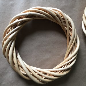 May include: A natural woven wreath made of light brown twigs, perfect for decorating a door or wall.
