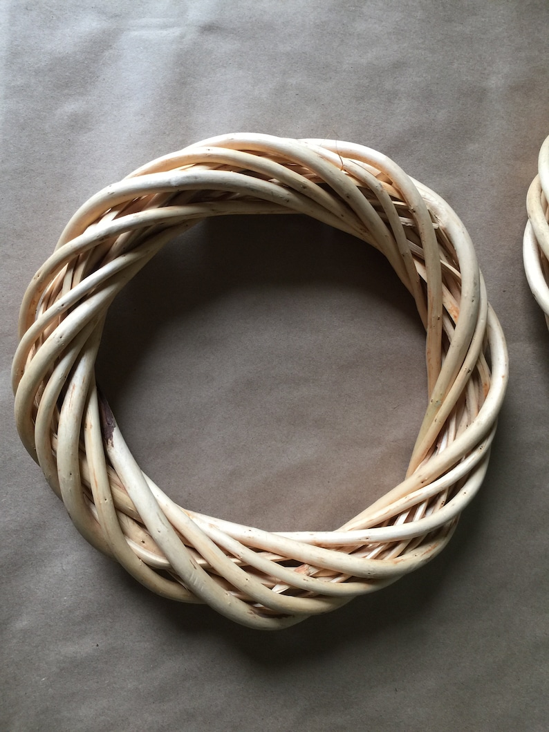 May include: A natural woven wreath made of light brown twigs, perfect for decorating a door or wall.