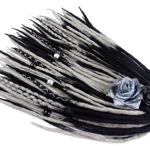 Puede incluir: Dreadlocks de lana negra y gris con cuentas plateadas y negras, una rosa azul y plateada y una rosa negra.
