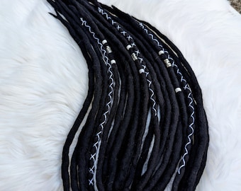 Peut inclure: Dreadlocks en laine noire avec des coutures blanches et des perles argentées. Les dreadlocks sont attachées ensemble avec un élastique noir.