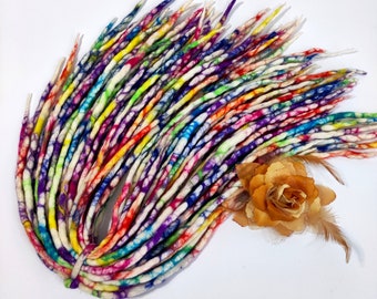 May include: A bundle of colorful wool dreadlocks with a white base and a tie-dye pattern. The dreadlocks are arranged in a circle and have a variety of colors, including red, orange, yellow, green, blue, and purple.