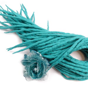 Puede incluir: Un paquete de rastas de lana azul turquesa, también conocidas como rastas de lana, para extensiones de cabello. Las rastas están dispuestas en una espiral suelta y están listas para ser añadidas al cabello.