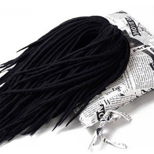 May include: A large bundle of black wool dreadlocks, displayed on a white pillow with black and white text that reads "MOVE QUEEN".