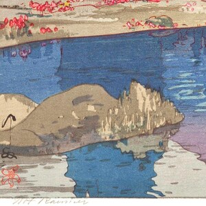 May include: A colorful woodblock print depicting a serene waterscape. The artwork features a blue river reflecting the sky, with a rocky outcrop and a shoreline adorned with pink blossoms. The print has a signature in the bottom right corner.