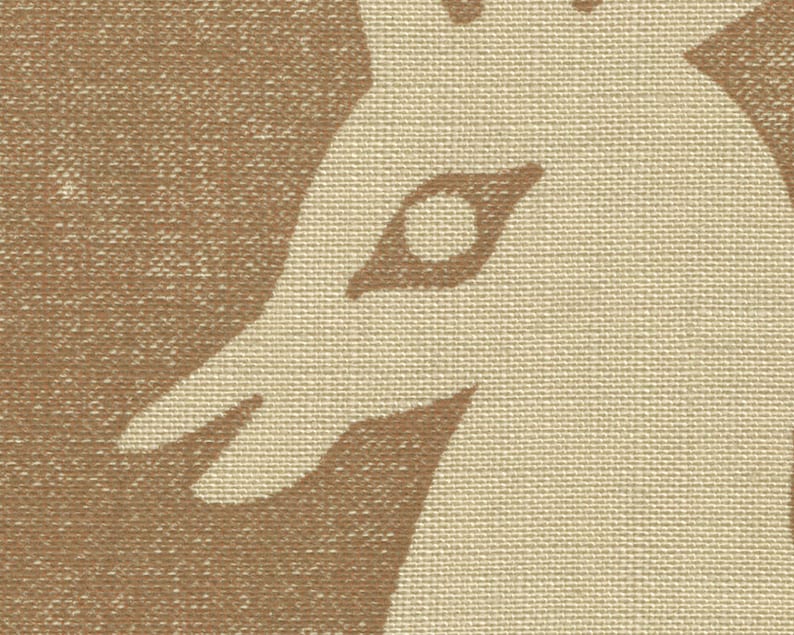 Puede incluir: Primer plano de una tela beige con un contorno marr&oacute;n de la cabeza de un ciervo. El ojo del ciervo es visible y est&aacute; contorneado en marr&oacute;n.