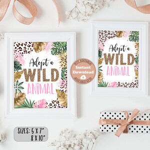 May include: Two printable signs with a jungle theme. The signs are white with a pink and gold leopard print border. The text on the signs reads "Adopt a Wild Animal". The signs are available in two sizes: 5x7 inches and 8x10 inches.