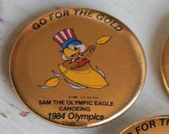 Ir por el oro Sam El Águila Olímpica Canotaje Pinback Botón Pin L.A. Juegos Olímpicos de 1984