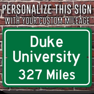 May include: Green road sign with white text that reads "Duke University 327 Miles".