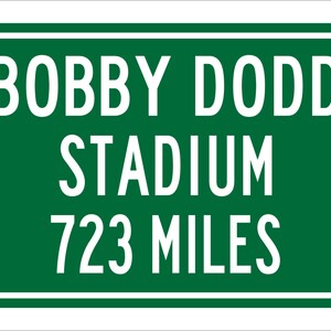 May include: Green road sign with white text that reads "BOBBY DODD STADIUM 723 MILES".