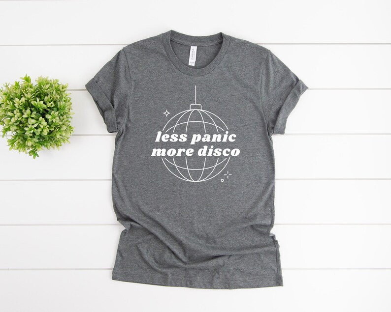 May include: A dark gray t-shirt with a white disco ball graphic and the text "less panic more disco".