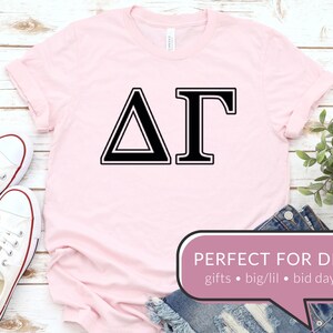 May include: Pink t-shirt with a black Delta Gamma sorority Greek letter design. The text "PERFECT FOR DIY" is in a speech bubble with the words "gifts, big/lil, bid day".