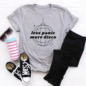 May include: A gray t-shirt with a black and white graphic of a disco ball and the text "less panic more disco".