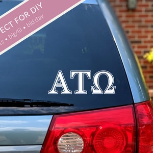 May include: White vinyl decal with the letters "ATO" on a blue car window.