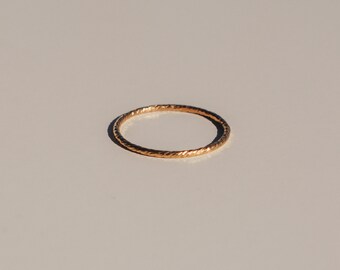 May include: A simple gold band ring with a textured, rope-like design.