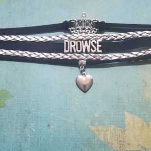 May include: Black choker necklace with a silver crown charm, a silver heart charm, and the word "DROWSE" in silver lettering.