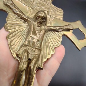 K&ouml;nnte beinhalten: Ein goldfarbenes Metallkreuz mit einer detaillierten Darstellung von Jesus Christus. Das Kreuz hat ein Sonnenstrahlendesign und aufwendige Details.