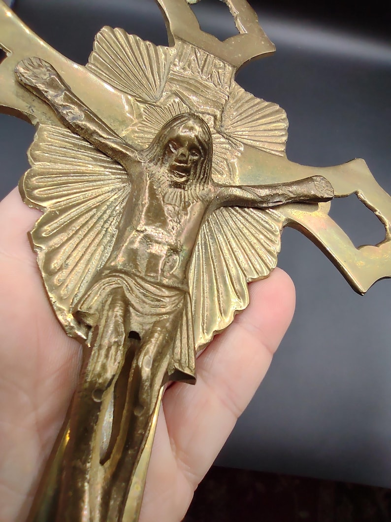 K&ouml;nnte beinhalten: Ein goldfarbenes Metallkreuz mit einer detaillierten Darstellung von Jesus Christus. Das Kreuz hat ein Sonnenstrahlendesign und aufwendige Details.