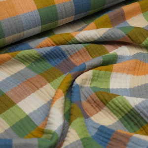 Könnte beinhalten: Ein weicher, strukturierter Stoff mit einem karierten Muster in Blautönen, Grün, Orange und Beige.