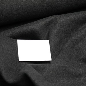 May include: A white blank card on a dark grey fabric background.