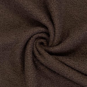 Könnte beinhalten: Ein dunkelbrauner Stoff mit einer dichten, strukturierten und lockigen Oberfläche. Das Material ist in einer zentralen Spirale angeordnet, die die Tiefe und die gleichmäßige dunkelbraune Farbe des flauschigen, fleeceartigen Textils zeigt.