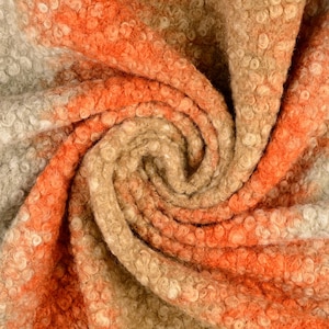 Könnte beinhalten: Nahaufnahme eines weichen, flauschigen Stoffes mit einem Farbverlauf von Orange zu Beige. Der Stoff ist strukturiert und hat ein wirbelndes Muster.