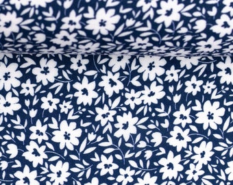 May include: White floral pattern on a dark blue fabric. The fabric has a small-scale floral print with white flowers and leaves on a navy blue background.