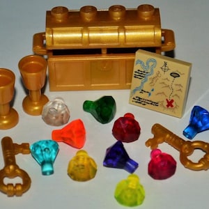 May include: A collection of toy pirate-themed accessories, including a gold treasure chest, two goblets, a map, keys, and colorful gems. The map features a hand-drawn design with a red X marking a spot. The gems are various colors.