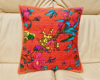 Könnte beinhalten: Quadratisches orangefarbenes Kissen mit einem Blumendesign in Pink, Türkis und Gelb. Das Kissen hat ein gestepptes Muster und einen orangefarbenen Rand. Das Kissen liegt auf einem cremefarbenen Sofa.