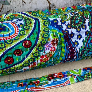 May include: A vibrant yoga mat and strap set, showcasing a paisley pattern in blue, green, red, and white. The design is enhanced with detailed stitching. The strap echoes the mat's colourful design.