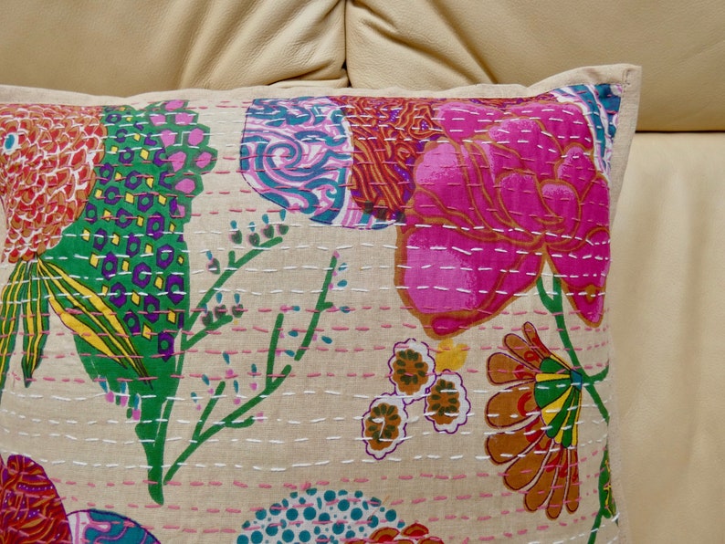 Puede incluir: Una funda de coj&iacute;n de algod&oacute;n beige con un patr&oacute;n floral. El patr&oacute;n presenta flores y hojas rosas, verdes, amarillas, naranjas y azules. La funda de coj&iacute;n est&aacute; decorada con costuras blancas.
