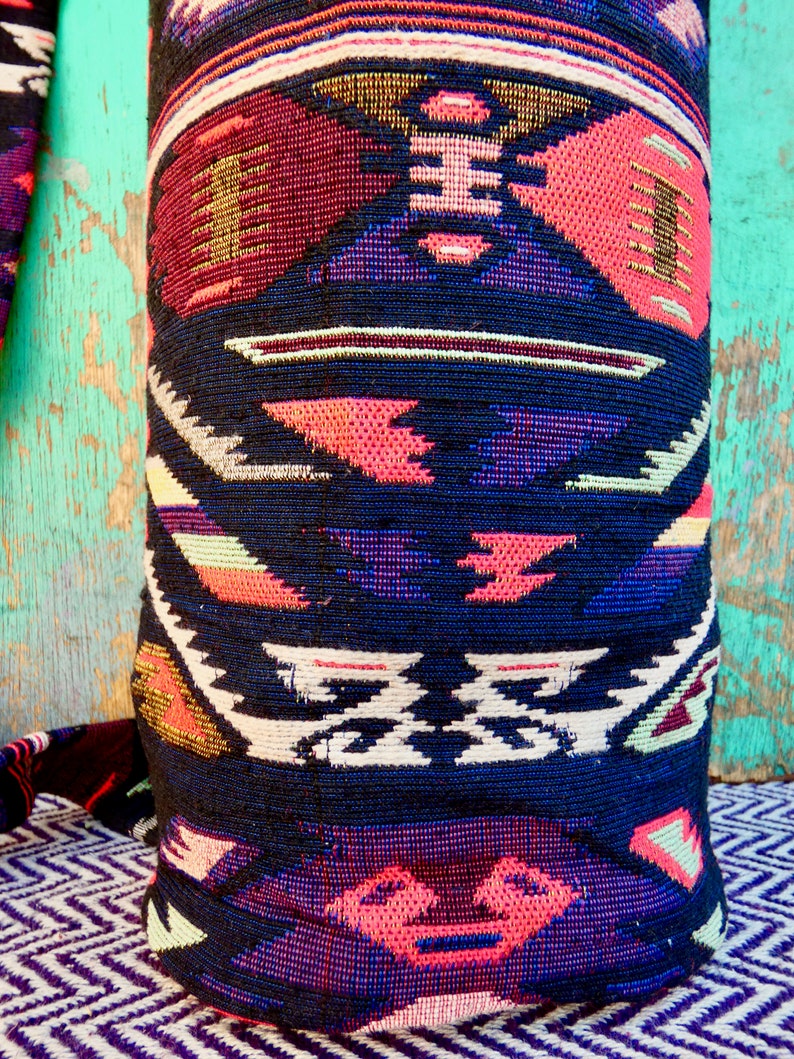 May include: A black and red patterned pillow with geometric designs. The pillow is made of a woven fabric with a textured surface.