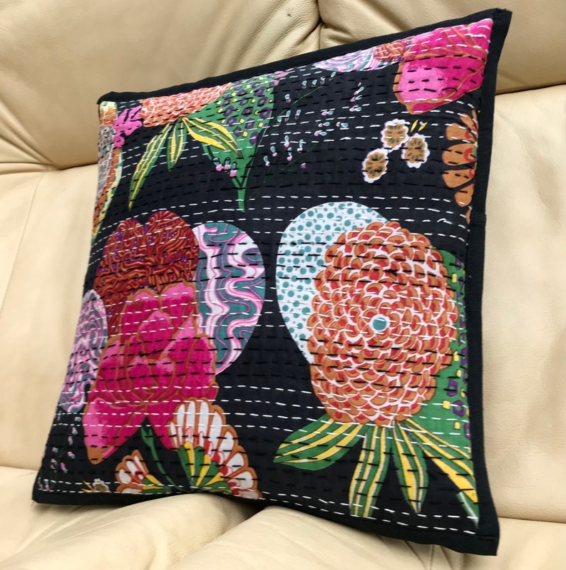 May include: Black cotton pillow cover with a floral pattern in shades of pink, orange, green, and white. The pillow cover is quilted with a black thread and has a black border.