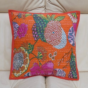 Peut inclure: Coussin carr&eacute; orange avec un motif floral rose, vert et bleu. Le coussin a une bordure rouge et est fait d'un tissu matelass&eacute;. Le motif comprend des fleurs et des fruits stylis&eacute;s.