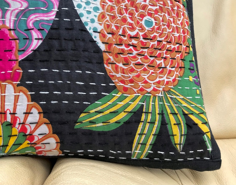 May include: Black cotton pillow cover with a floral pattern in shades of pink, red, green, yellow, and white. The pillow cover is quilted with white thread and has a black border.