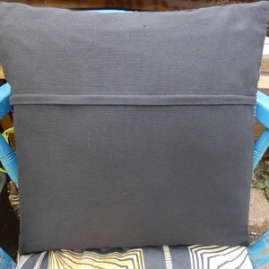 Puede incluir: Coj&iacute;n cuadrado negro con una costura cosida en el medio. El coj&iacute;n est&aacute; sobre una silla azul con un asiento estampado. La parte trasera del coj&iacute;n es de tela negra lisa.