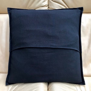 May include: A black pillow with a zipper closure on the back. The pillow is made of a soft, textured fabric.