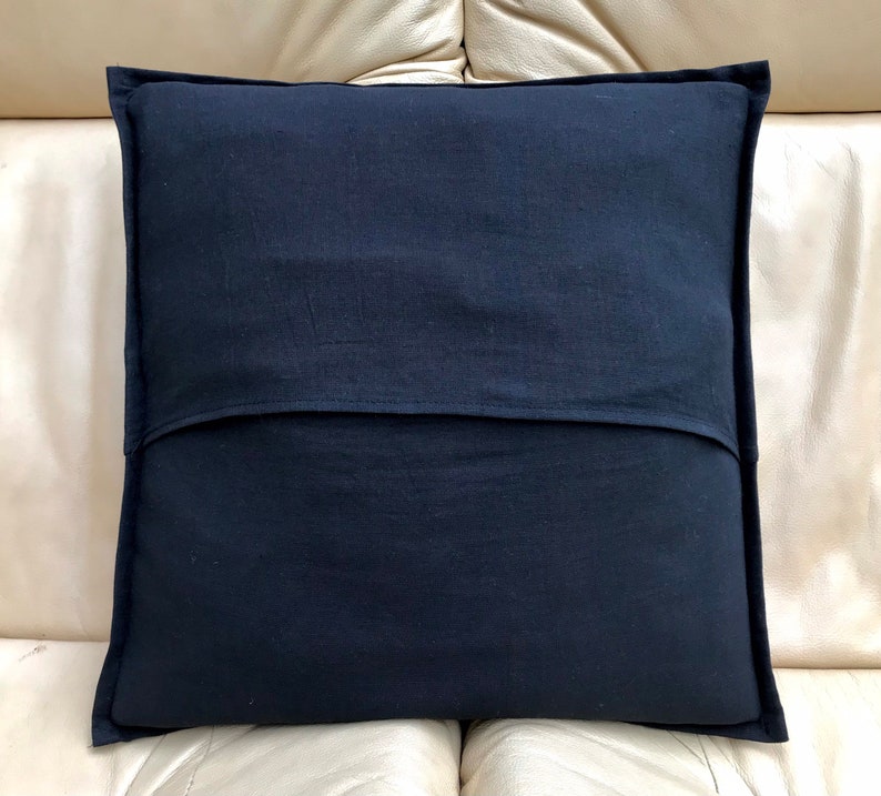May include: A black pillow with a zipper closure on the back. The pillow is made of a soft, textured fabric.