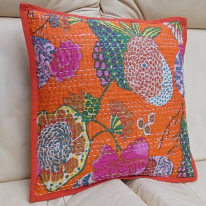 Peut inclure: Coussin carr&eacute; orange avec un motif floral rose, vert et bleu. Le coussin a une bordure rouge et des coutures blanches. Le coussin mesure environ 45 cm de c&ocirc;t&eacute;.